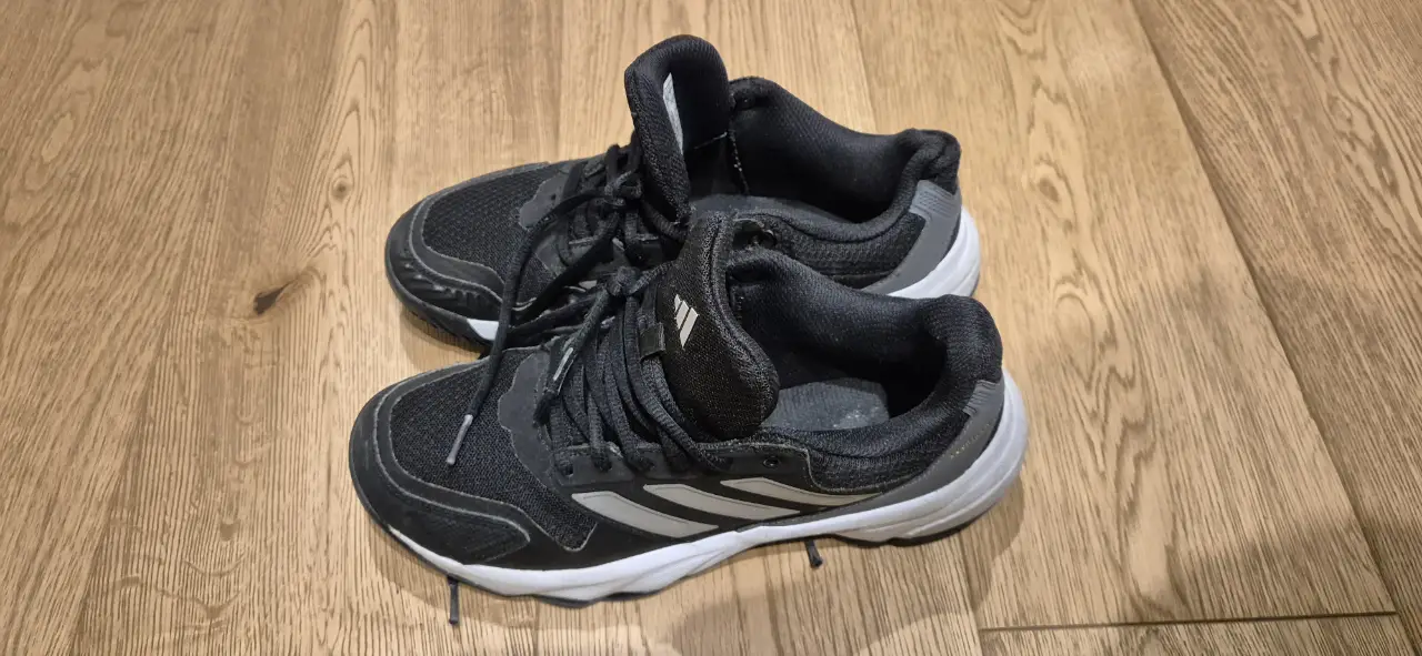 Zapatillas Adidas negras con detalles en blanco y gris. Ideales para actividades deportivas.