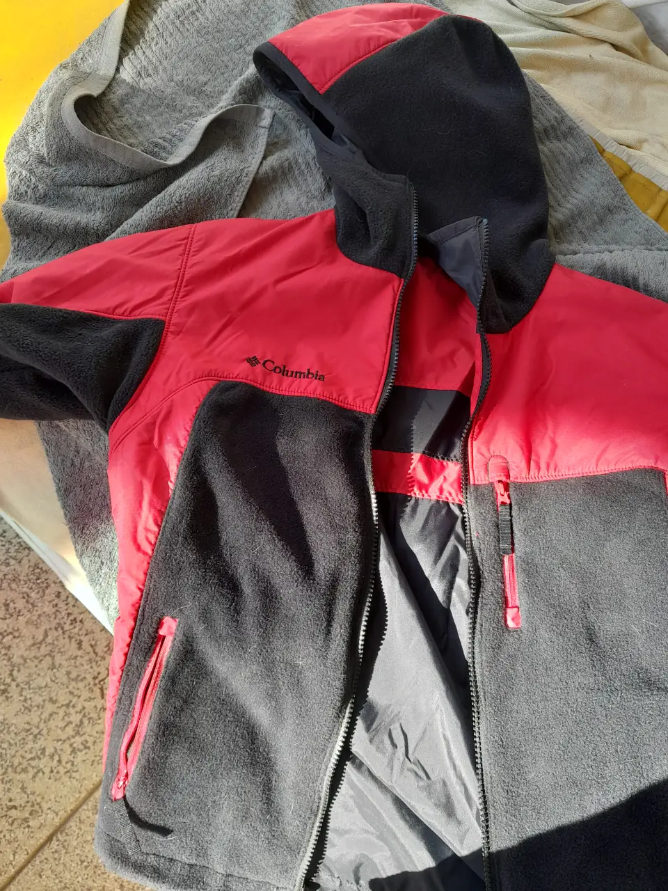 Campera Columbia para hombre, combinada en rojo y negro, con cierre y capucha. Ideal para actividades al aire libre y uso diario.