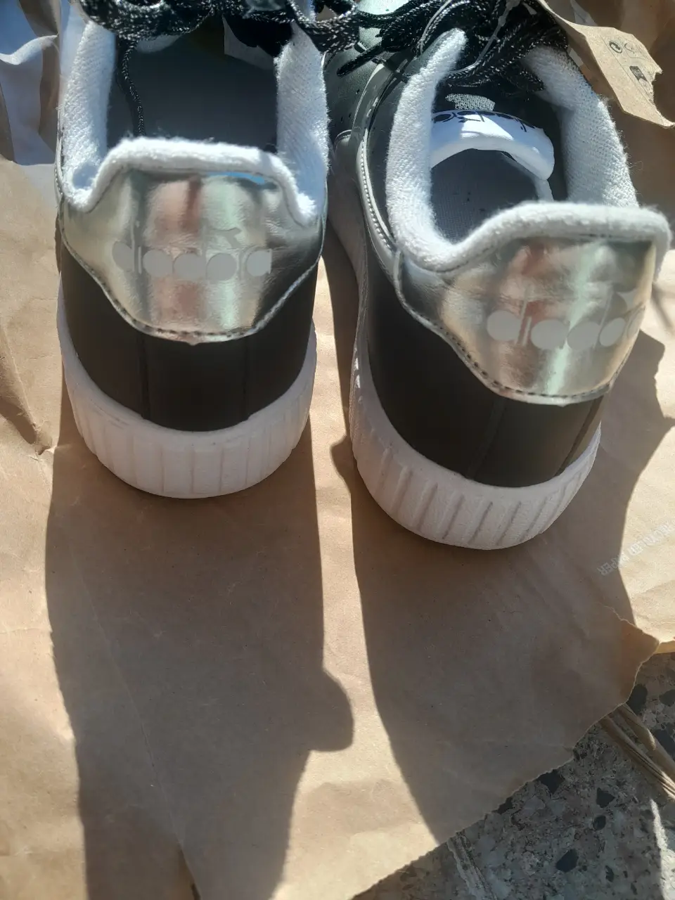 Zapatillas Diadora negras con detalles plateados y suela blanca. Ideales para un look casual y moderno.