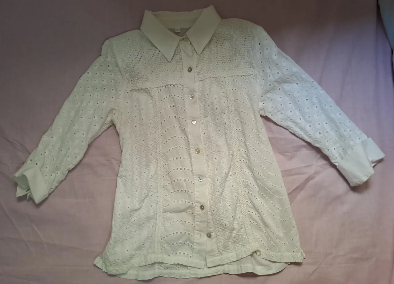 Camisa blanca de broderie con mangas largas y detalles calados. Un clásico infalible para cualquier ocasión, ideal para un look fresco y elegante.