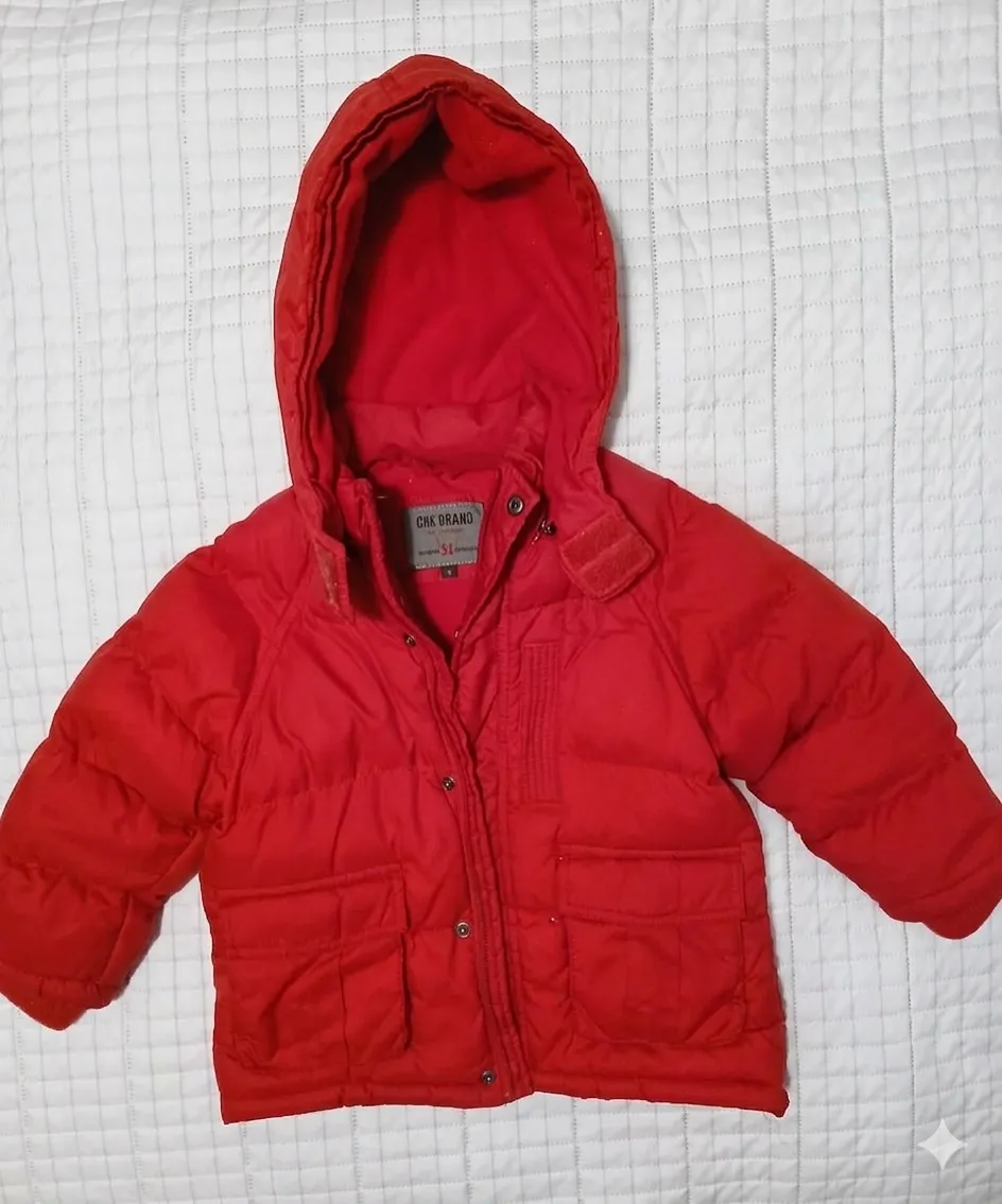Campera puffer roja con capucha para bebé. Tiene bolsillos frontales con solapa y cierre a botones.