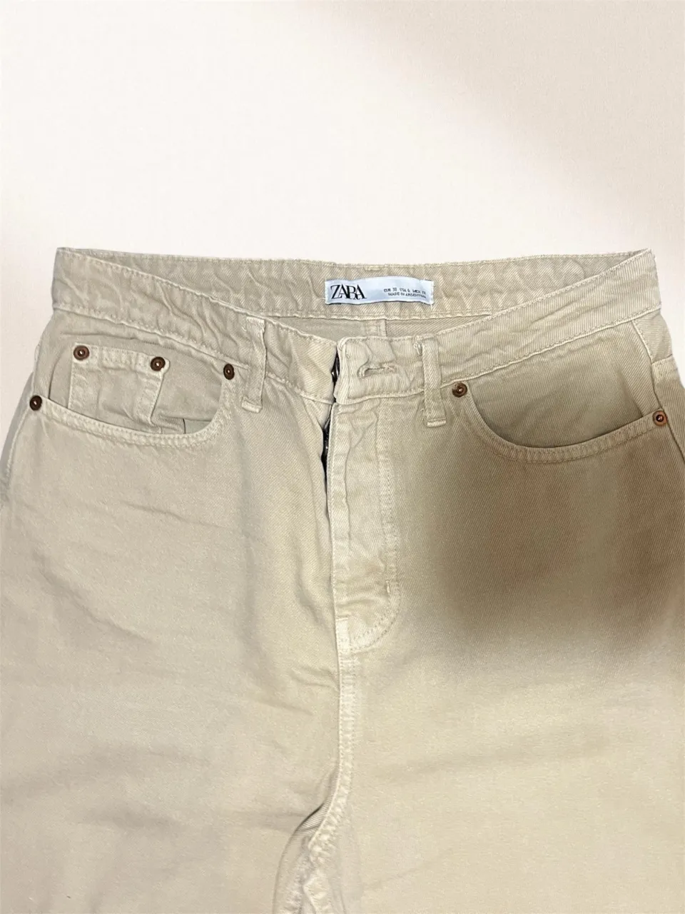 Jeans tiro alto color beige, corte recto y relajado.