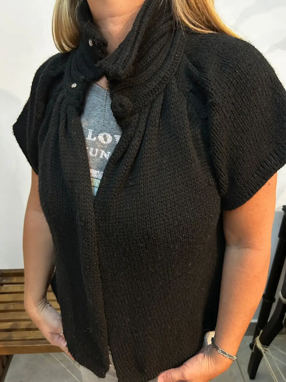 Capita negra de lana con cuello alto y mangas cortas. Diseño drapeado y detalles abotonados. Ideal para un look elegante y abrigado. talle único 