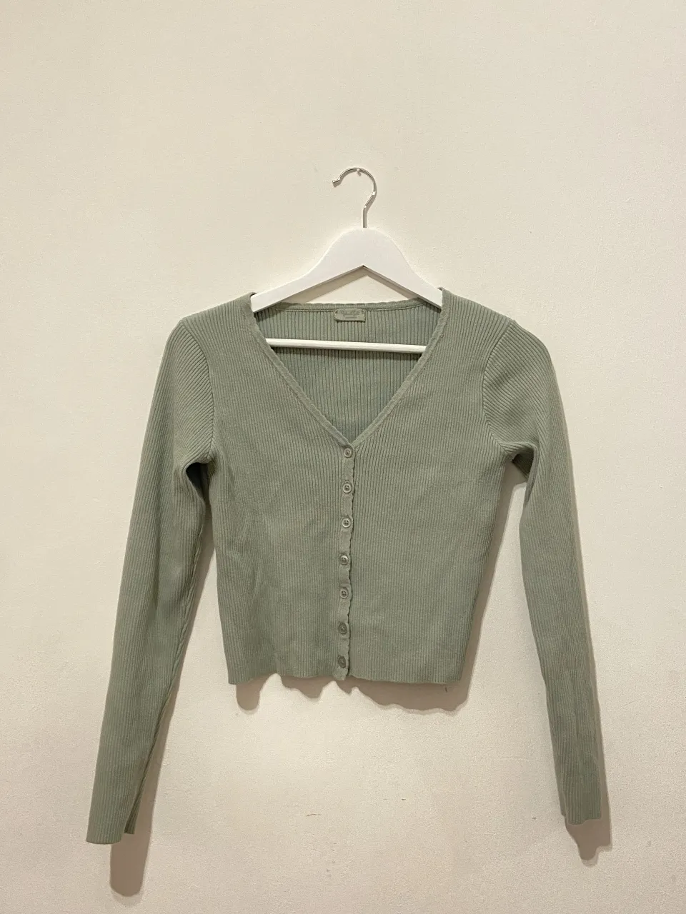 Cardigan de punto canalé en color verde. Tiene botones en la parte delantera y mangas largas. Ideal para un look casual y cómodo.