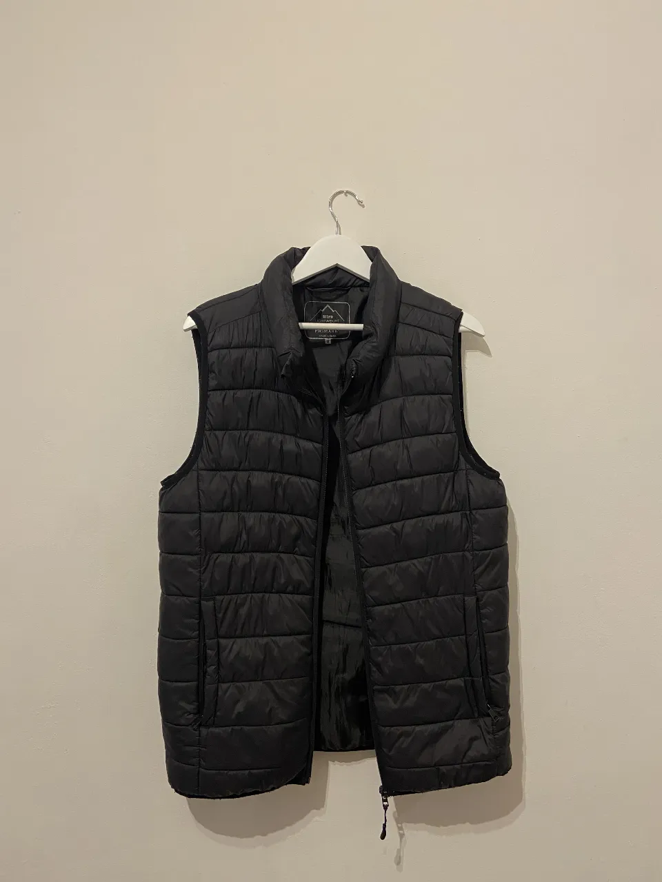 Chaleco acolchado negro para hombre, ideal para el invierno. Posee cierre y un bolsillo con cierre sin funcionar.