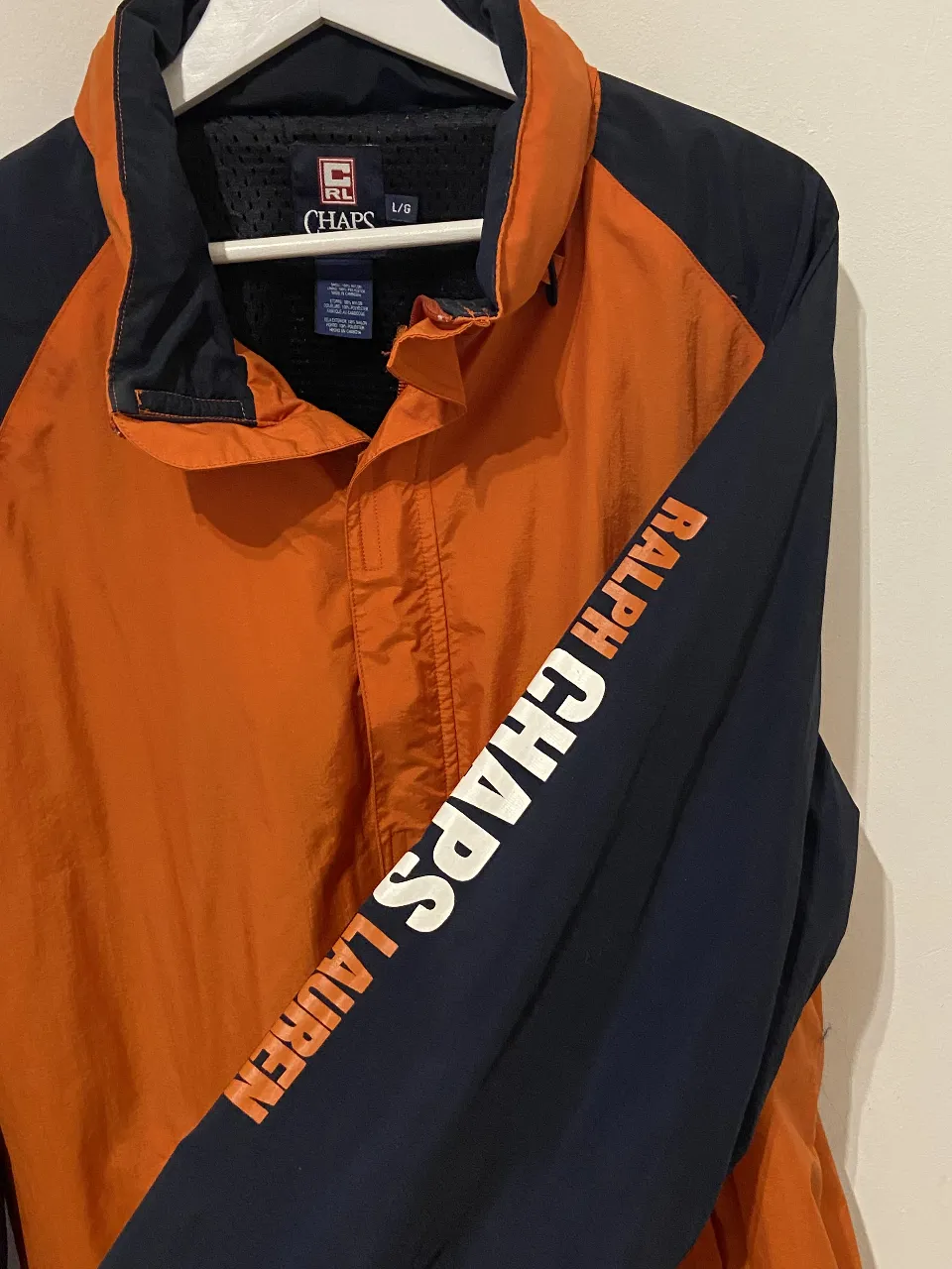 Campera rompeviento Chaps Ralph Lauren naranja y azul marino. Con detalles en blanco en la manga. Capucha escondida en el cuello. Perfecto estado. Ideal para actividades al aire libre.