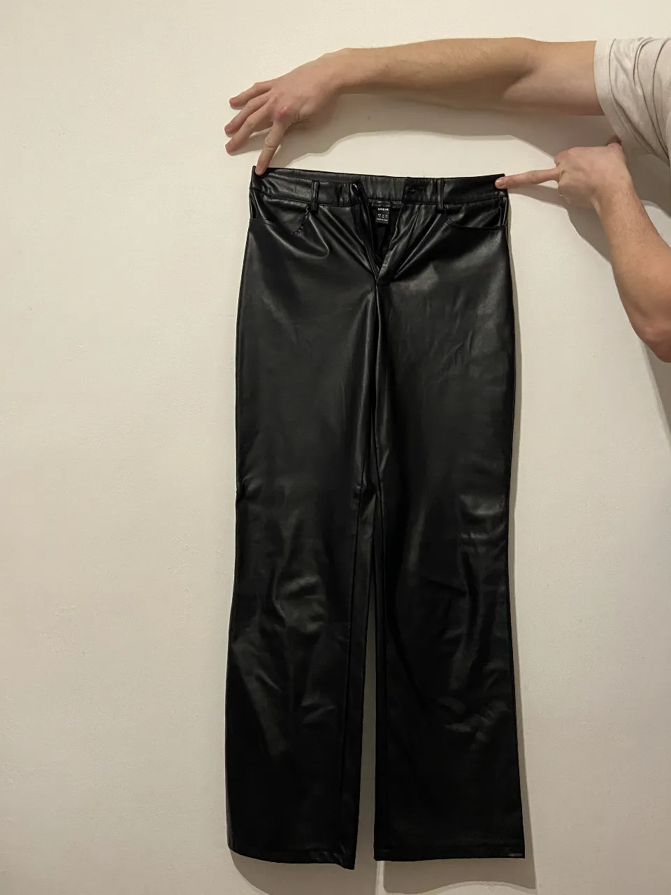 Pantalón de vestir de cuero sintético negro elastizado, tiro alto y corte recto. Por dentro es abrigado. Ideal para un look moderno y elegante.