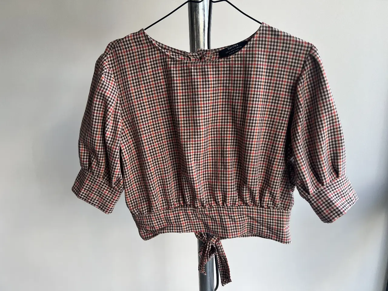 Blusa Bershka a cuadros, con mangas 3/4 abullonadas y detalle de lazo en la espalda. Ideal para un look casual y con estilo.