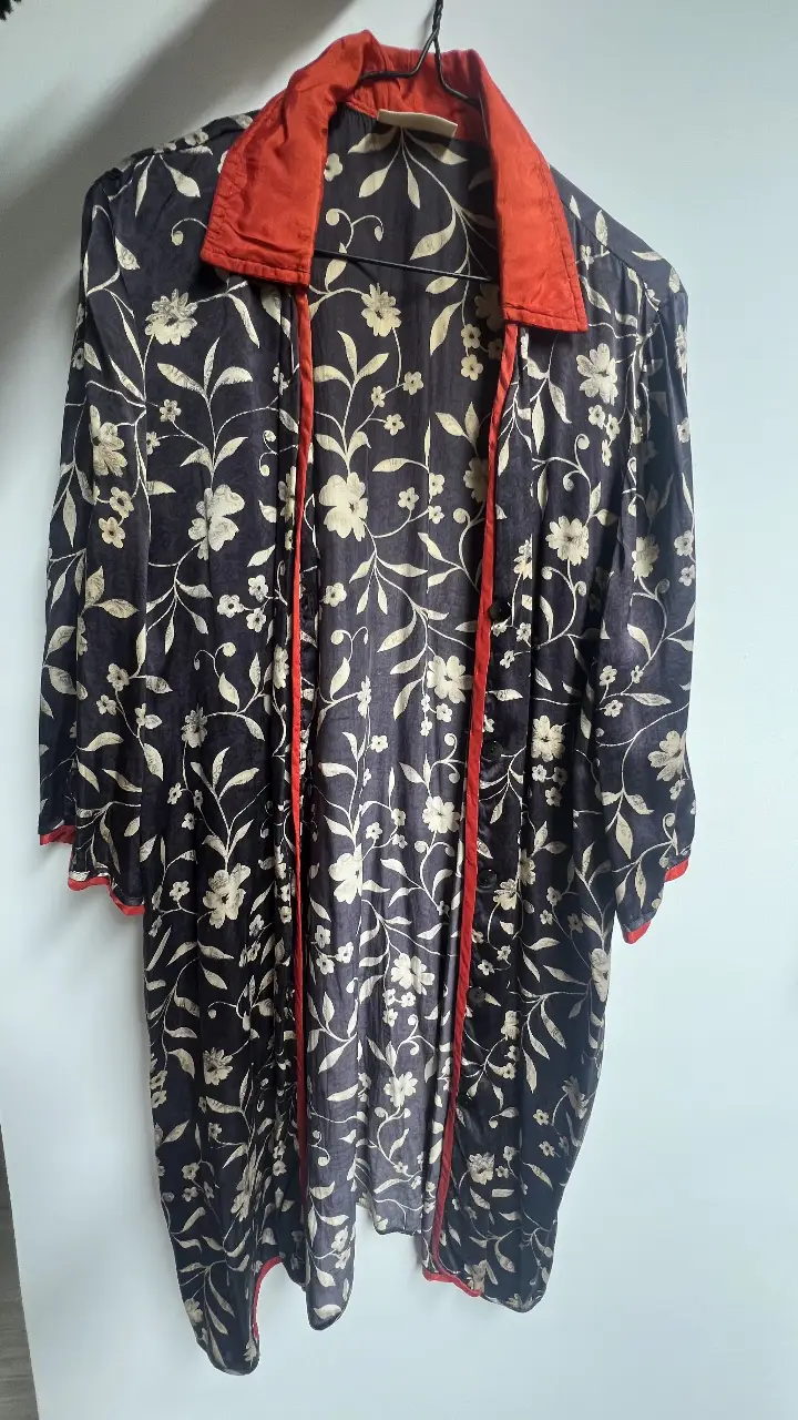 Kimono largo con estampado floral en tonos negro y beige, con detalles en rojo en el cuello y bordes. Ideal para un look bohemio y elegante.