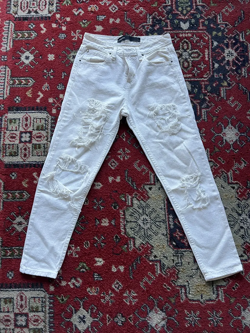 Jeans de mujer blancos con roturas. Tiro medio, corte recto. Marca UMA.