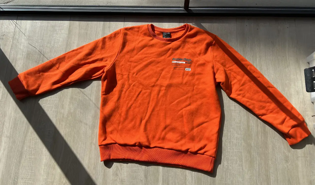Buzo de cuello redondo naranja de la marca Superflag. Confeccionado en algodón, ideal para un look casual y cómodo. Estampado con diseño en la parte delantera y trasera.