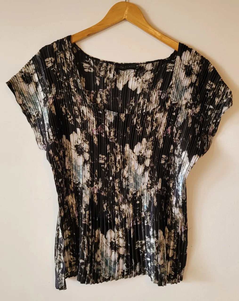 Remera de vestir, Gustavo Cassin, estampada con flores en tonos negros, blancos y grises. Posee un diseño plisado en toda la prenda y mangas cortas. 