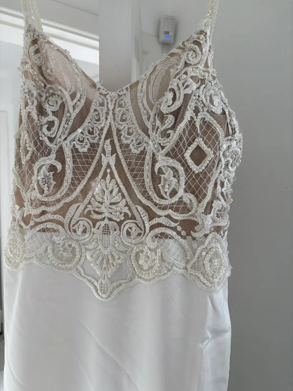 Vestido de novia blanco con detalles de encaje y pedrería en el corpiño. Falda fluida y elegante, ideal para un casamiento.