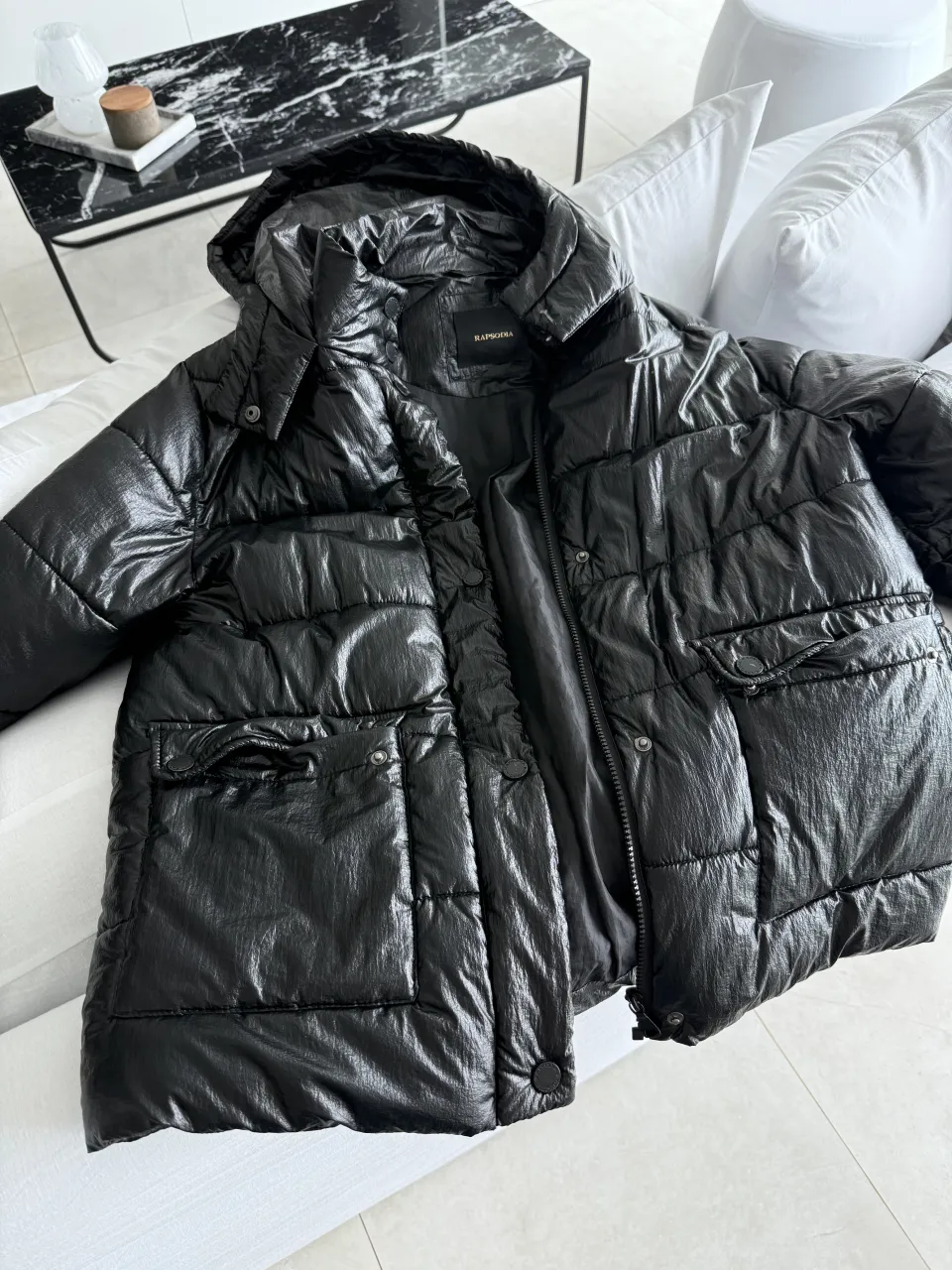 Campera de pluma negra, con capucha y bolsillos. Ideal para el frío y para un look urbano.