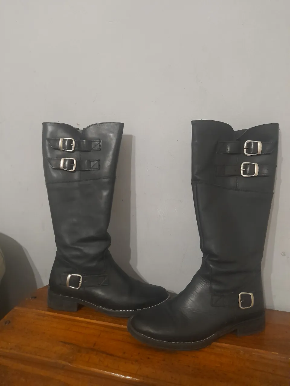 Botas de caña alta negras con hebillas y cierre lateral. Ideales para un look moderno y versátil.