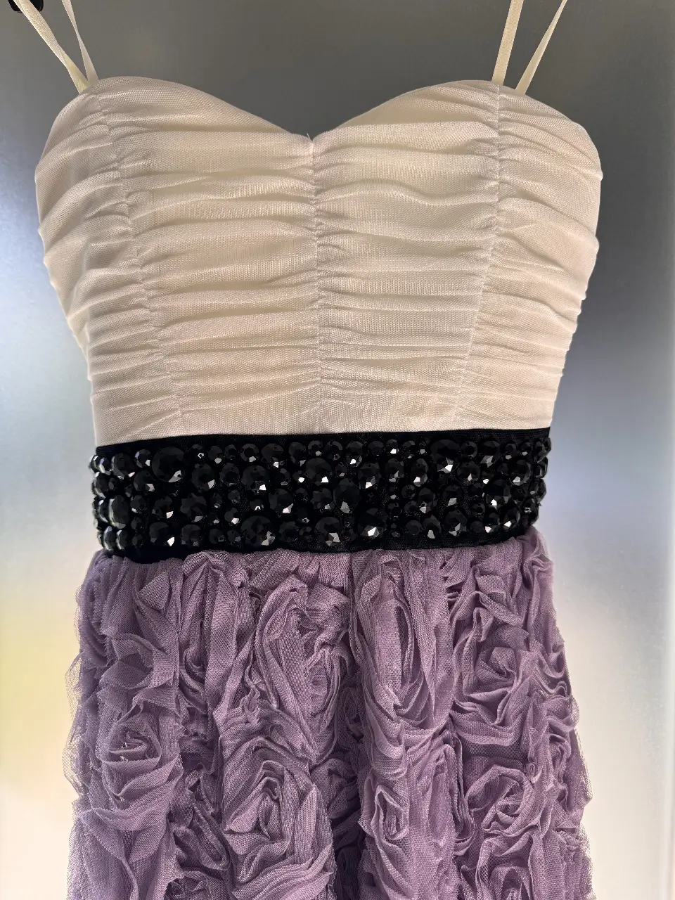 Vestido mini de fiesta con corpiño blanco fruncido y falda violeta con detalles de rosas. Cintura con apliques negros. Ideal para eventos especiales.