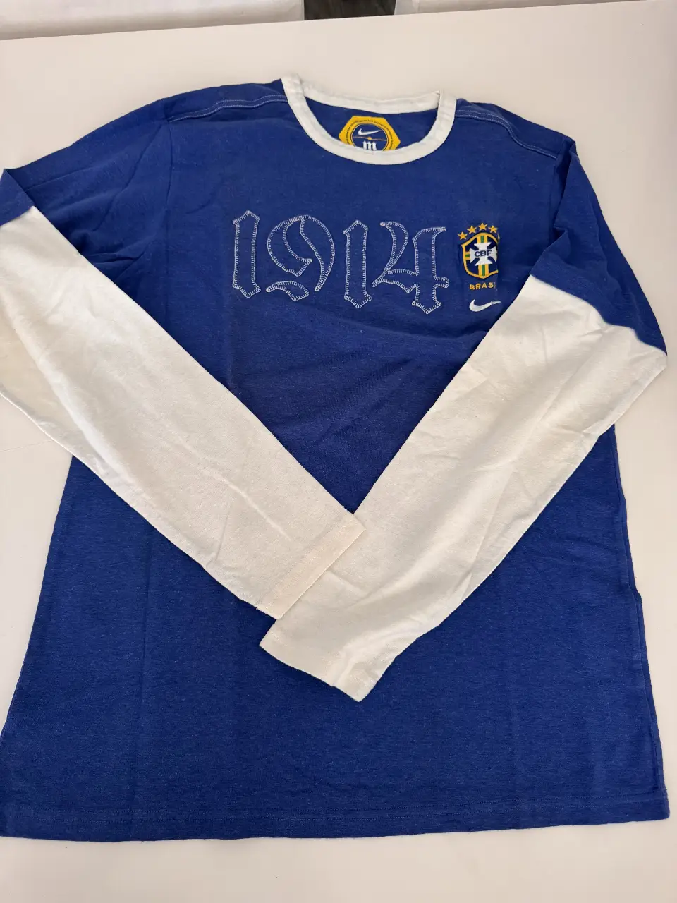 Remera manga larga de la selección de Brasil, con el número 1914 bordado en el frente y el escudo de la CBF. Cuello blanco y mangas blancas.