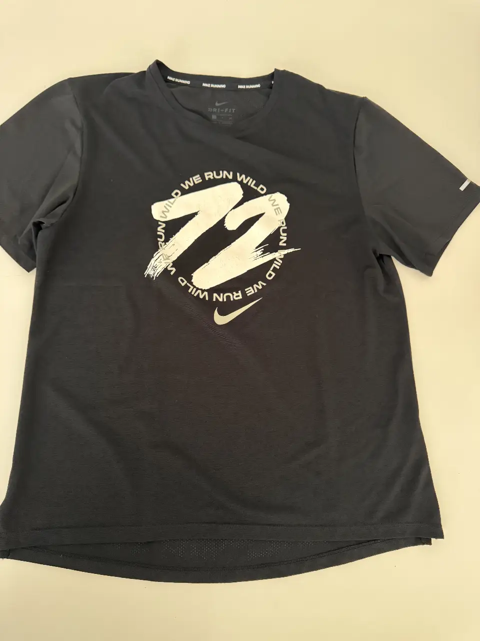 Remera deportiva Nike Dri-FIT para hombre, de manga corta, color negro con estampado blanco en el frente. Ideal para running y entrenamientos.
