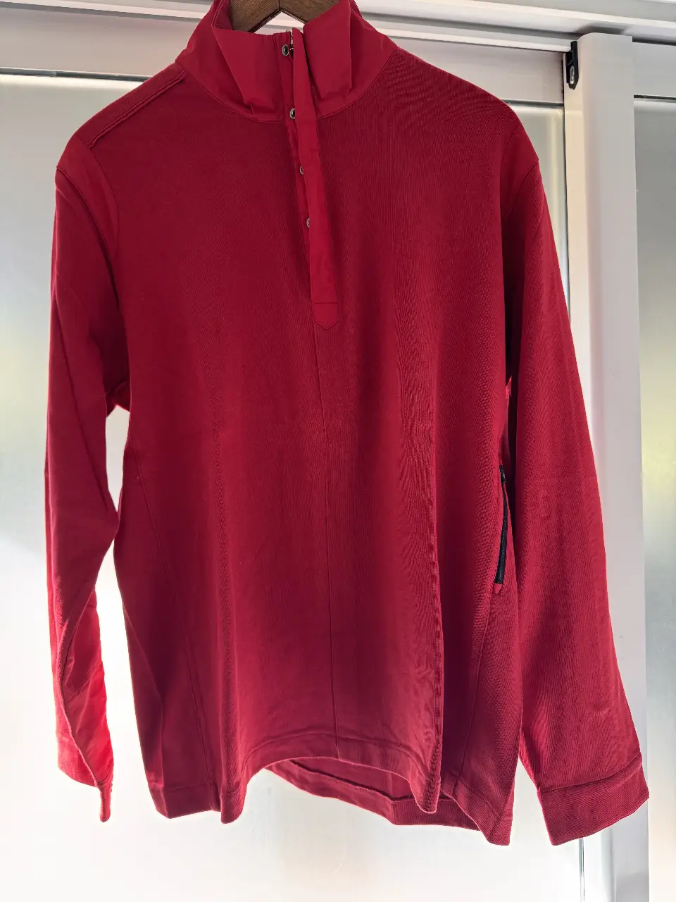 Buzo polera rojo de hombre, con cierre y bolsillo con cierre. Con logo de la marca en la manga.