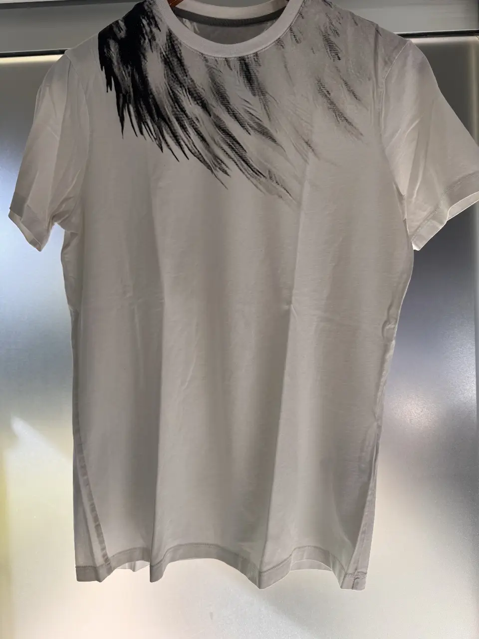 Remera blanca de hombre con estampado de diseño abstracto en el frente y un diseño de rostro en la espalda. De manga corta y cuello redondo, ideal para un look casual y moderno.