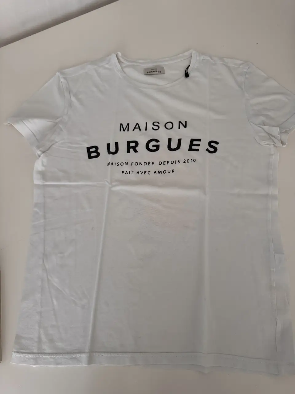Remera blanca de algodón con estampado "MAISON BURGUES" en negro. Corte clásico, ideal para un look casual y cómodo. Talle XS.
