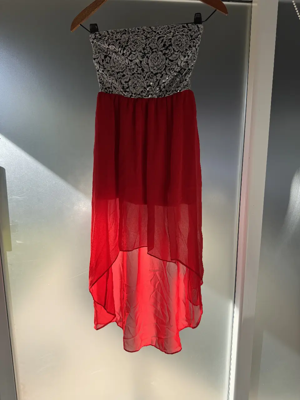 Vestido strapless de fiesta, con corpiño de encaje negro y plateado, y falda roja de gasa con corte asimétrico. Talle 3.