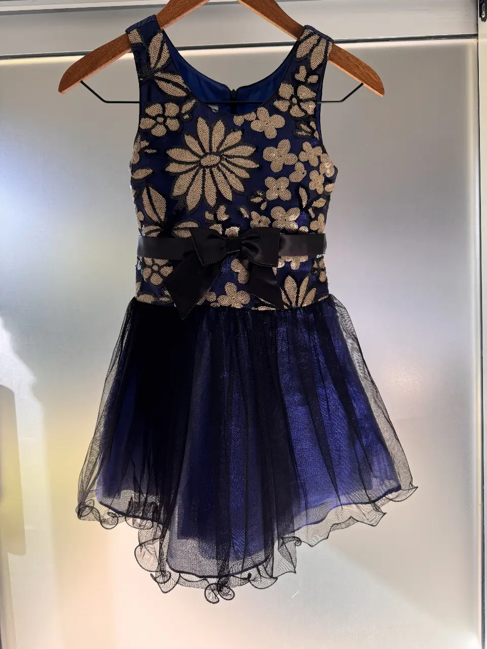 Vestido de fiesta para niña, con corpiño bordado con lentejuelas doradas sobre fondo azul. Cintura con lazo negro y falda de tul negro. talle 10