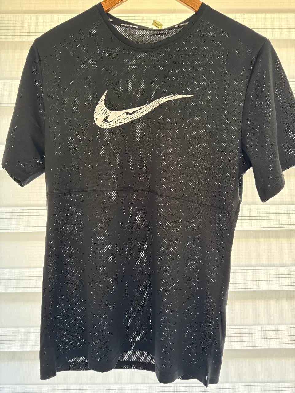 Remera deportiva Nike Dri-Fit para hombre, de manga corta y tejido perforado. Con el logo de la marca en blanco y detalles de costura. Ideal para running y entrenamientos.