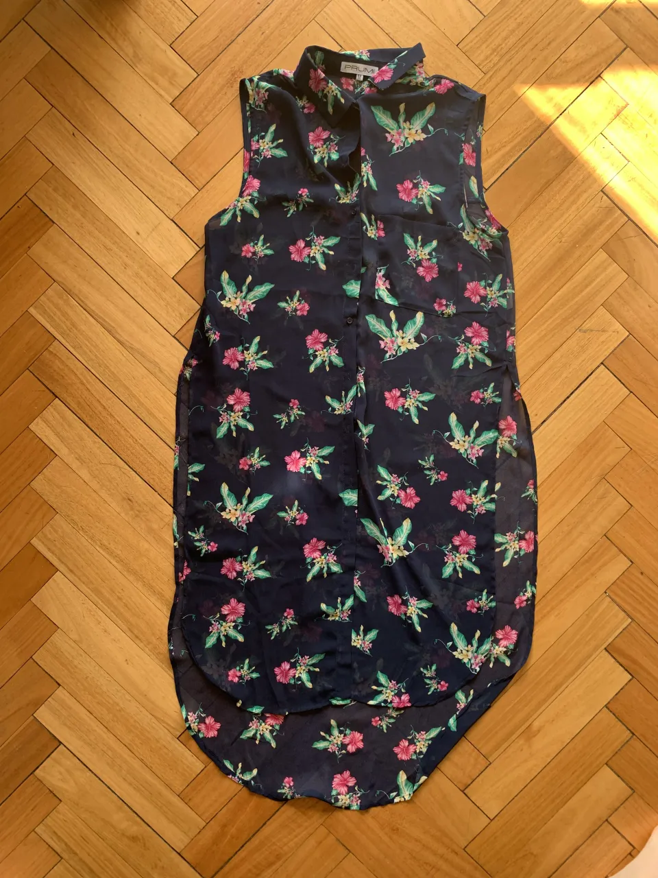 Remera sin mangas con estampa floral vibrante sobre fondo azul marino. Diseño fresco y moderno, ideal para días cálidos o para darle un toque de color a tu outfit. Perfecta para un look casual y descontracturado.