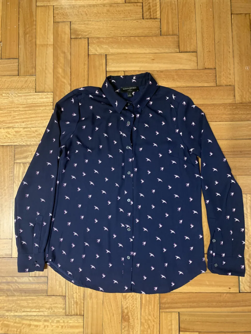 Camisa de manga larga azul marino con estampa de pajaritos blancos y rosas. Cuello clásico y botones al frente. Ideal para un look casual y canchero.