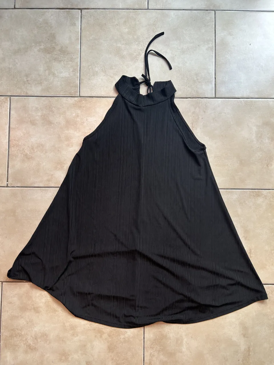 vestido negro con cuello halter y tiritas para atar en la nuca. la tela Elastiza y tiene una caída y textura divina 