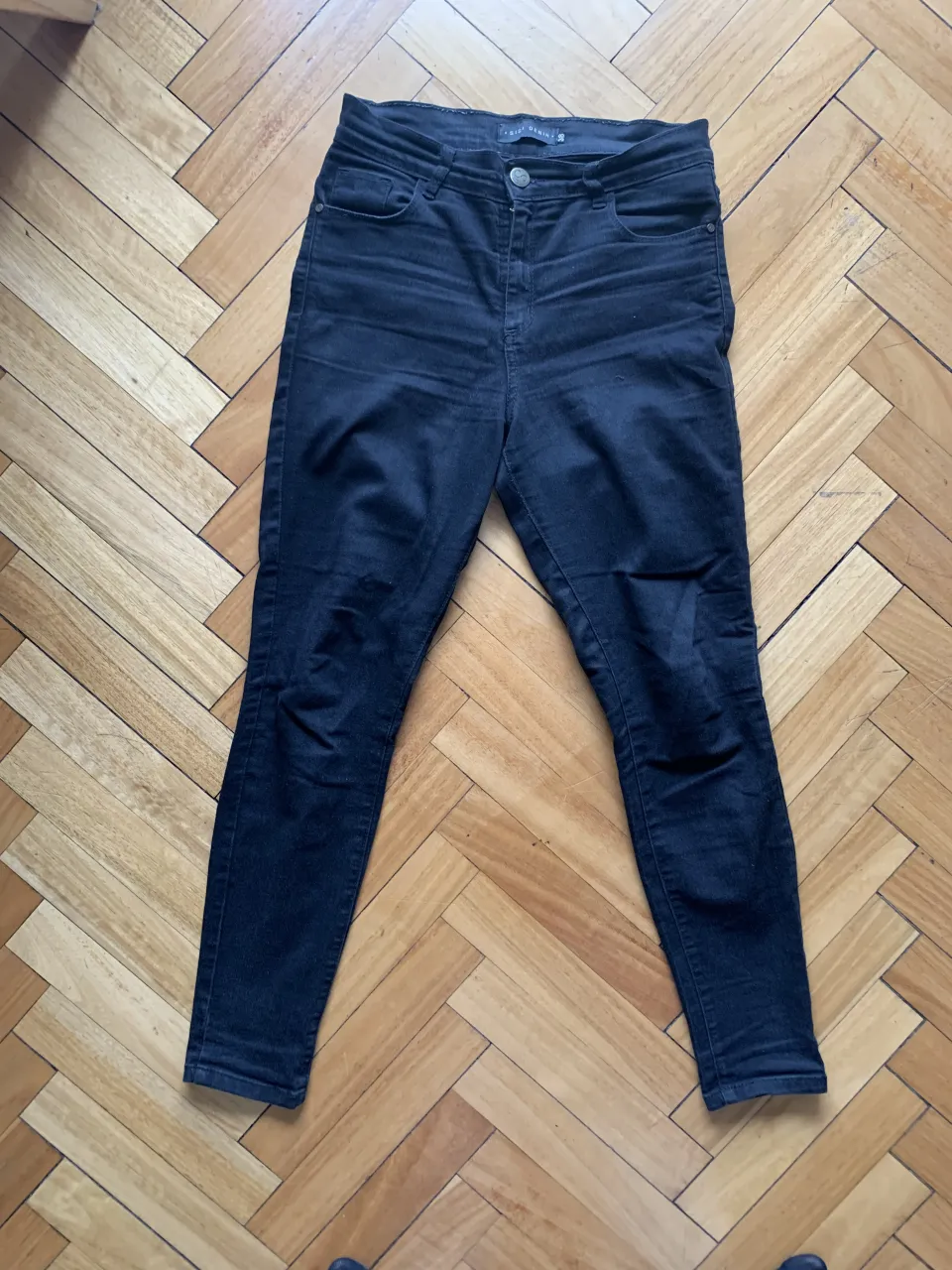 Jean tiro alto, corte chupín, color negro. Un básico indispensable para cualquier guardarropa, ideal para crear looks cancheros y modernos. Combinalo con tus tops y remeras favoritas.