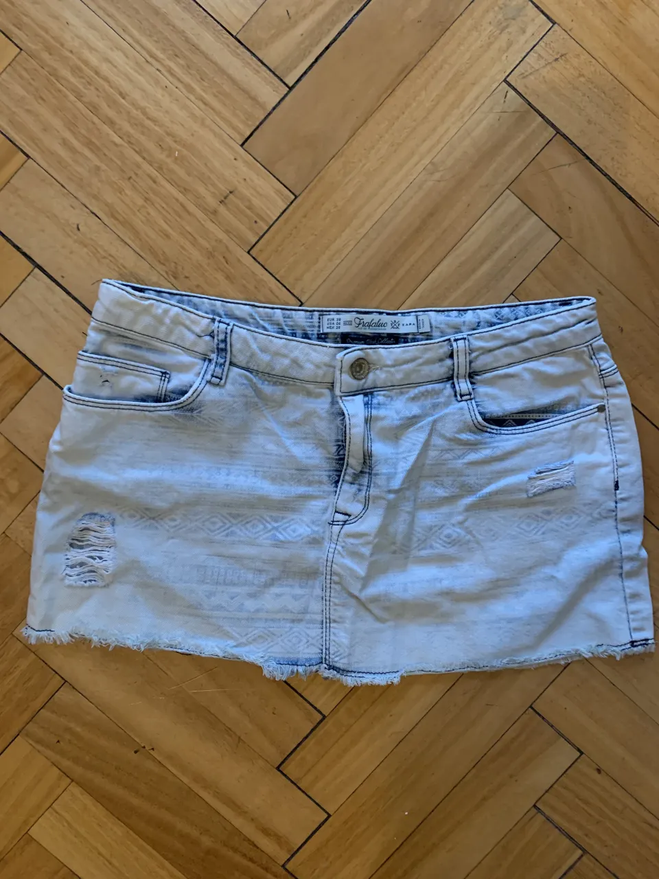 Short de jean tiro alto con roturas y detalles de bordado. Lavado desgastado y con terminación deshilachada.