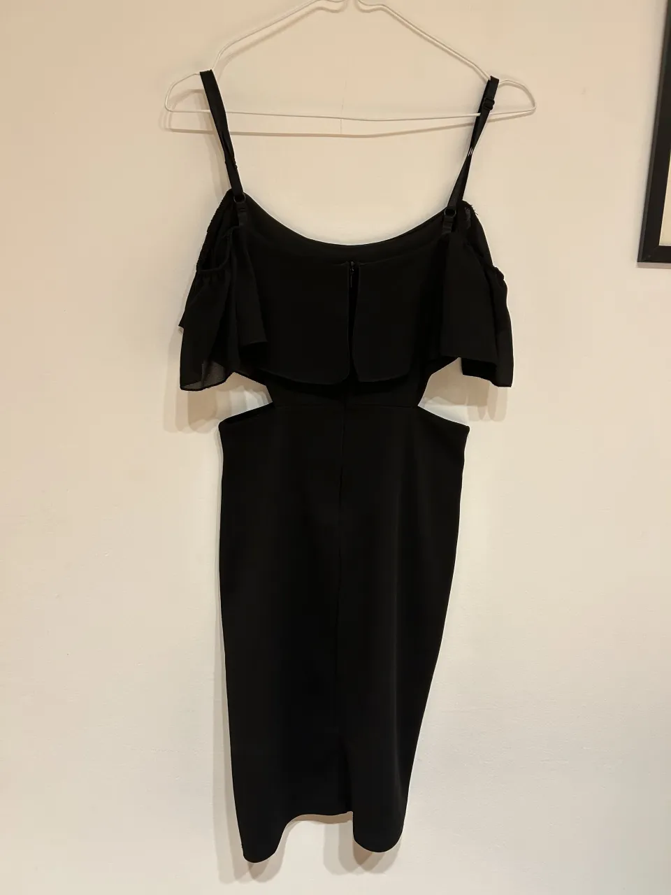 Vestido negro con detalles cut-out en la cintura y volados en los hombros. Ideal para una salida o fiesta.
