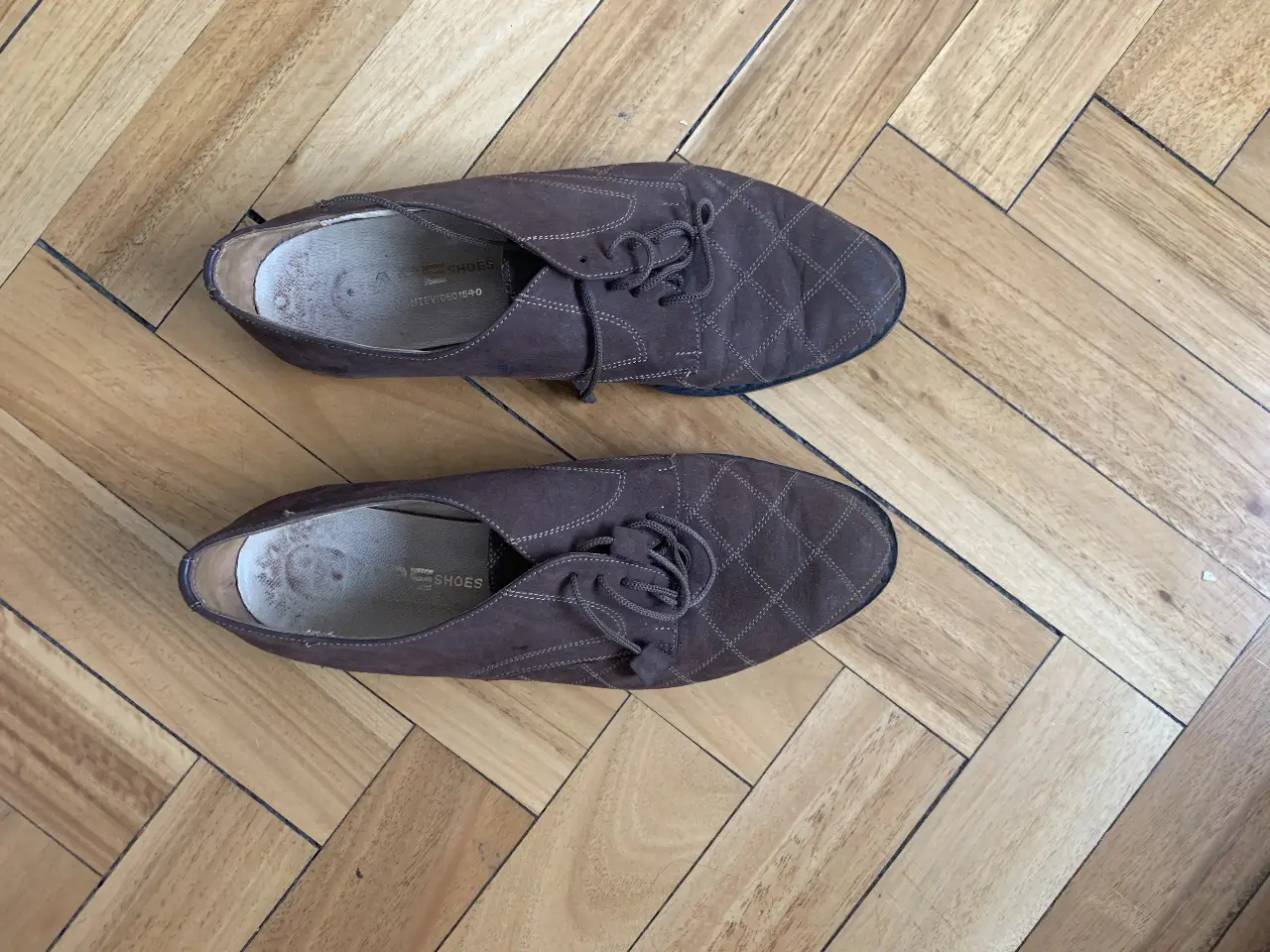 Zapatos  de cuero marrón con diseño de rombos. Tienen cordones y suela negra. Ideales para un look casual y elegante.