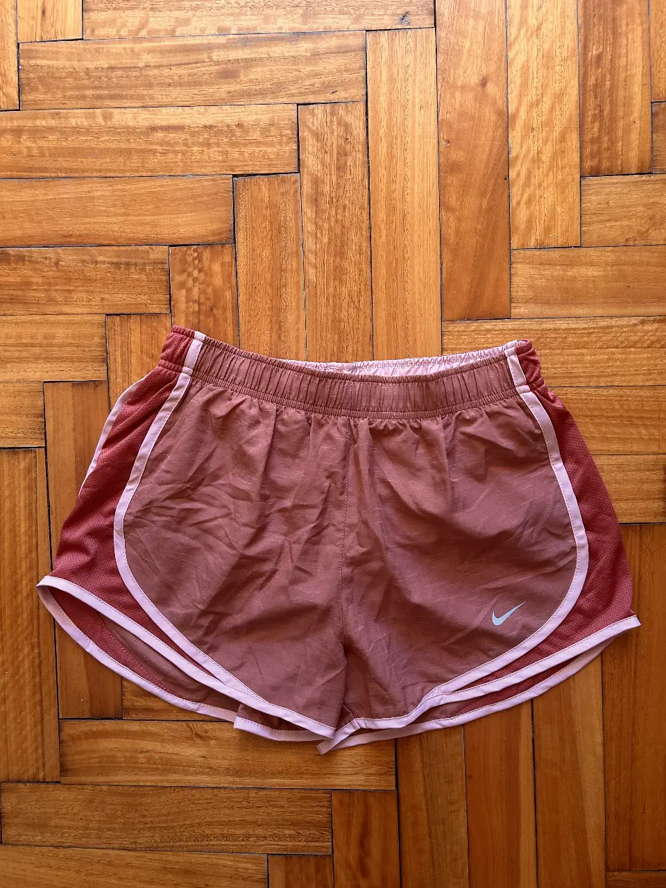 Short deportivo Nike Dri-Fit para mujer, color rosa con detalles en blanco. Ideal para running y entrenamientos.