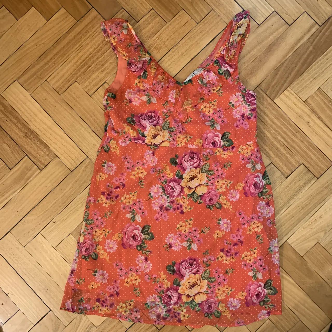 Vestido mini floreado en tonos naranja, rosa y amarillo. Con detalle de volados en los hombros y escote en V. Ideal para un look fresco y femenino.