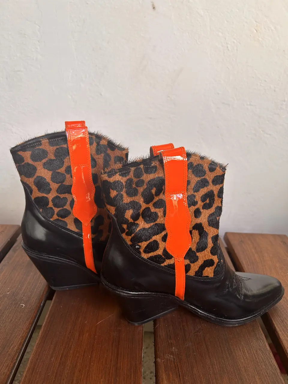 Botines de cuero con estampado de leopardo y detalles en naranja. Tienen taco y punta fina. Ideales para un look audaz y moderno.