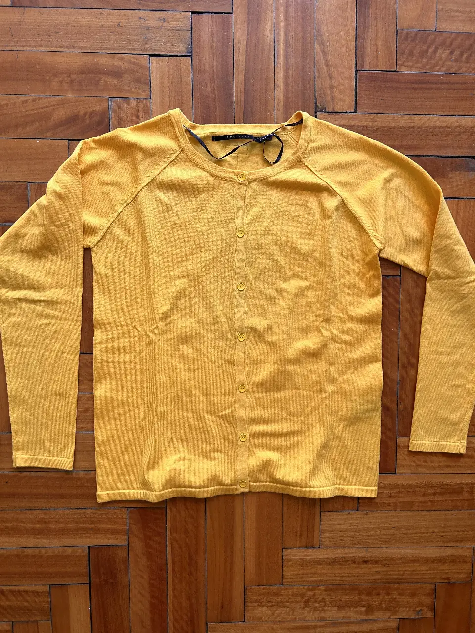 Cardigan amarillo de punto, con botones al frente y mangas largas. Ideal para un look casual y cómodo.