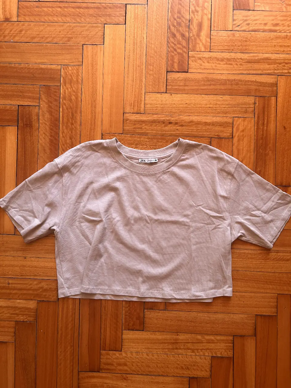 Remera crop de color crudo, de la marca Zara. Ideal para un look casual y cómodo. Confeccionada en un tejido suave y ligero, perfecta para el día a día.