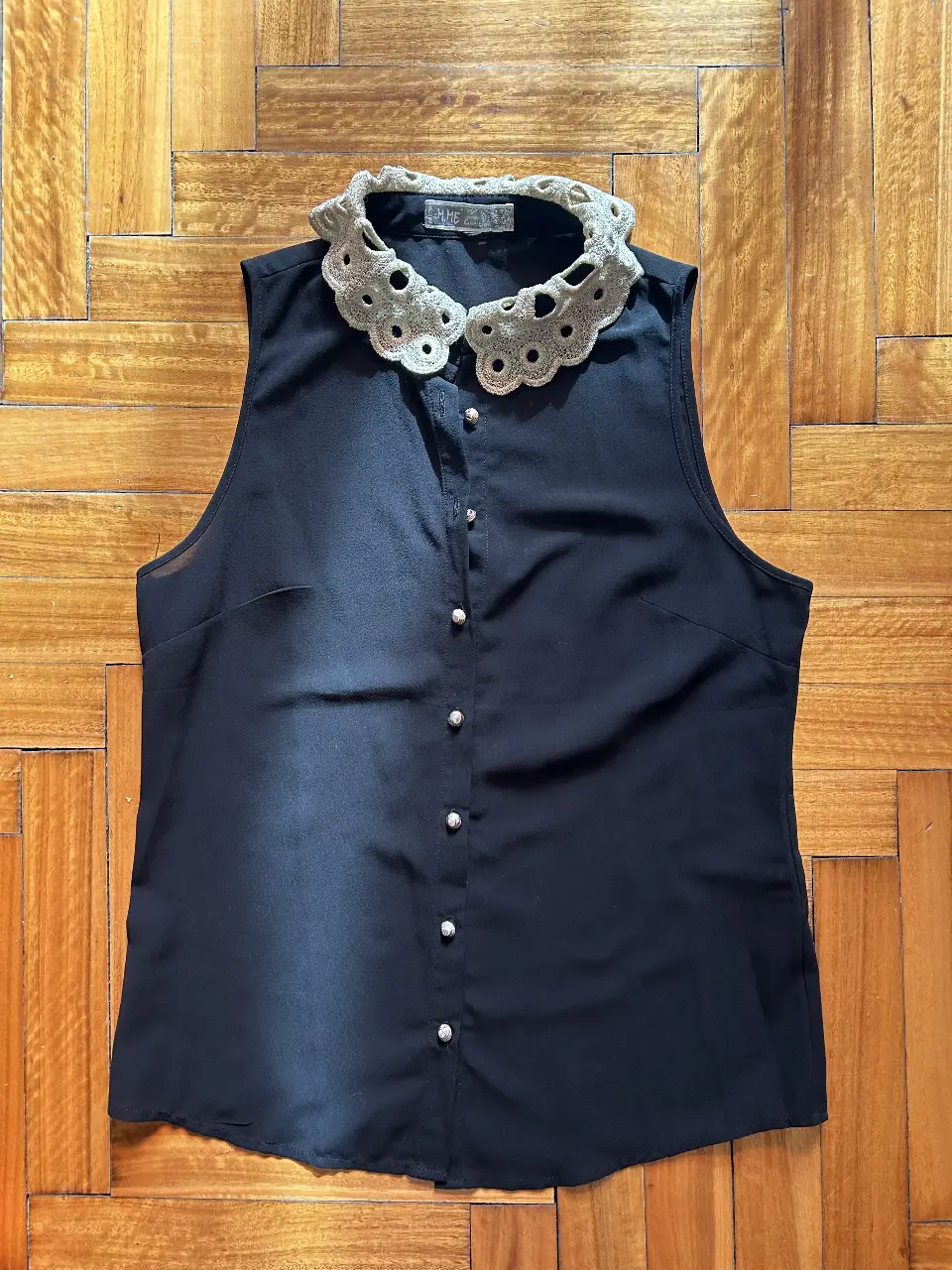 Blusa negra sin mangas con cuello Peter Pan de encaje. Ideal para un look elegante y sofisticado.