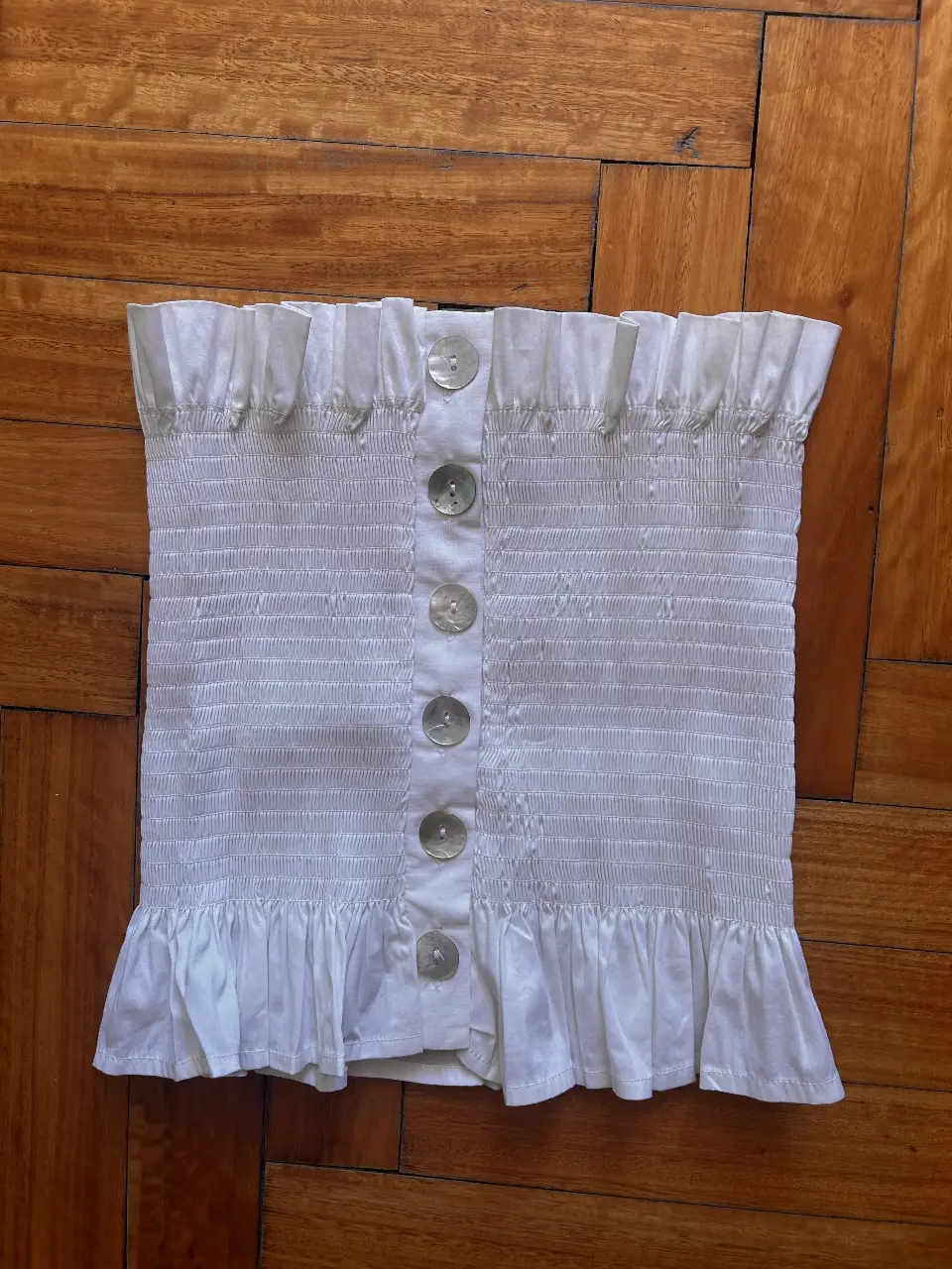 Top blanco con frunces y botones. Ideal para un look fresco y femenino. Perfecto para combinar con jeans o faldas.