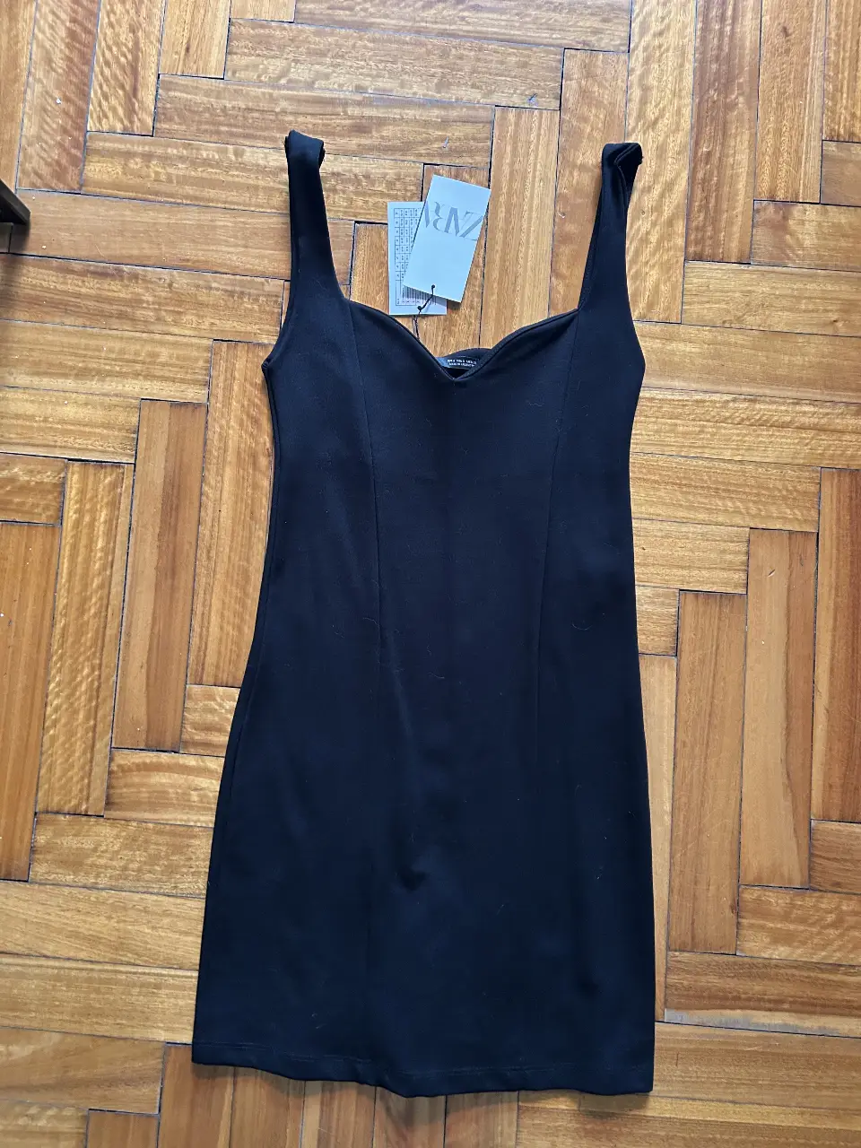 Vestido negro corto de Zara, con breteles anchos y escote en forma de corazón. Ideal para una salida o evento.