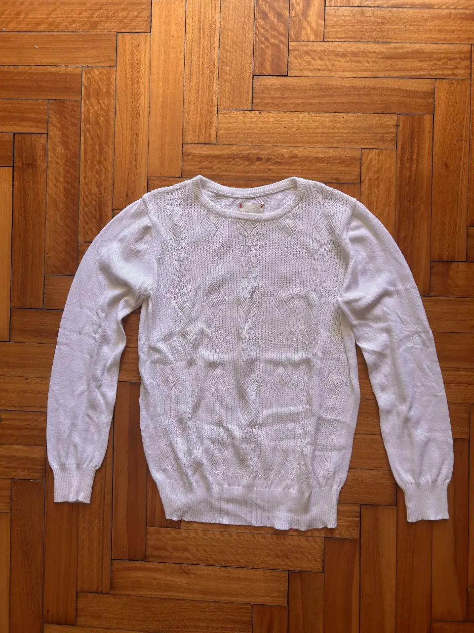 Sweater blanco de punto con detalles calados. Cuello redondo y mangas largas. Ideal para un look casual y cómodo.