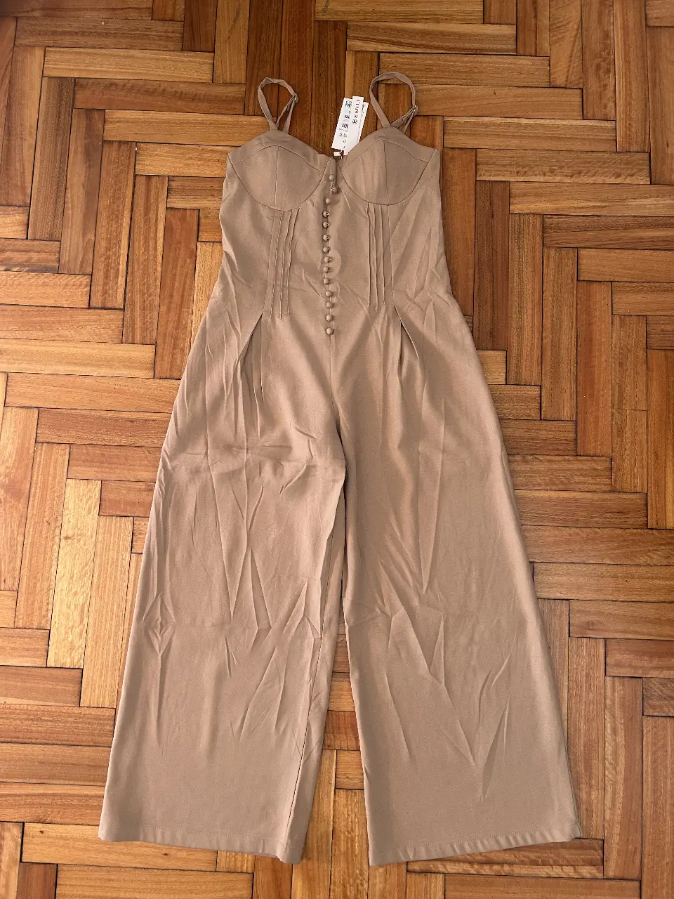 Mono largo de mujer, color marrón, con tirantes finos ajustables y botones delanteros. Corte entallado en la cintura y perneras amplias. Ideal para un look elegante y moderno.