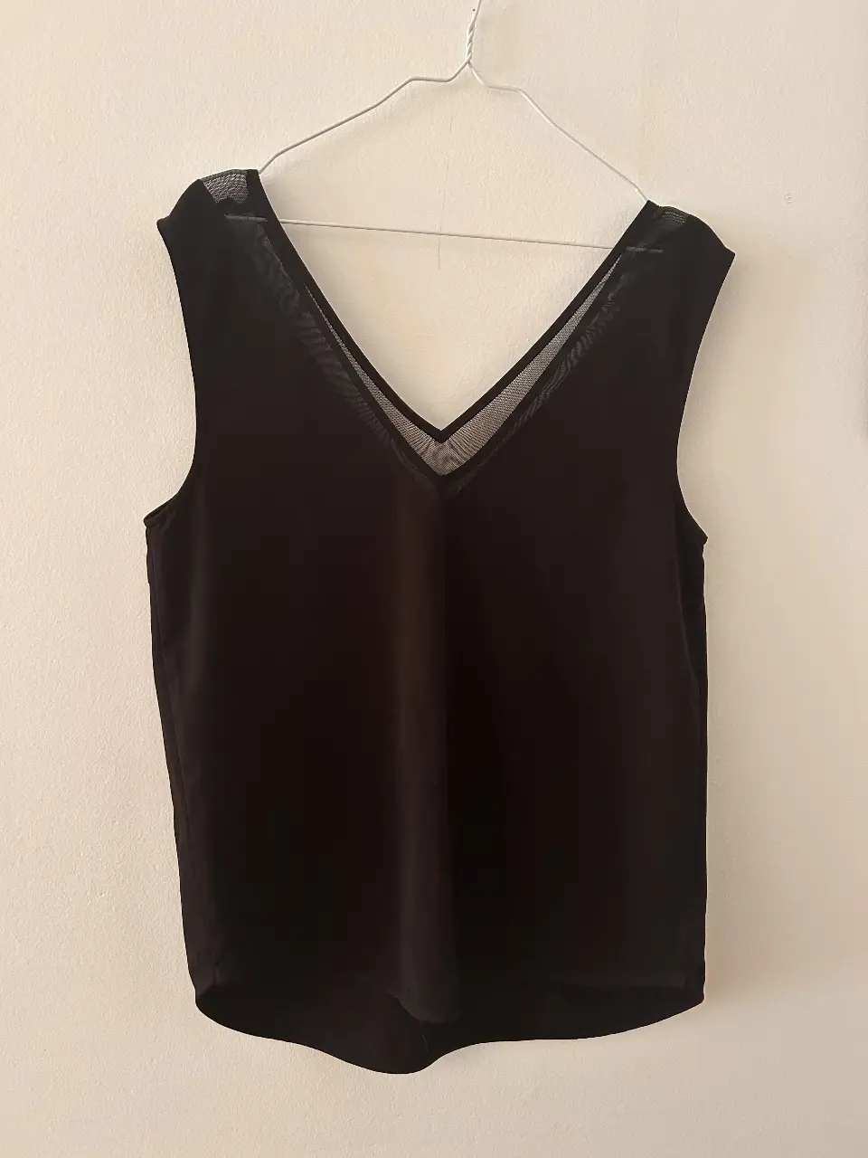 Top negro con escote en V y detalles de malla en los hombros. Ideal para un look elegante y moderno.