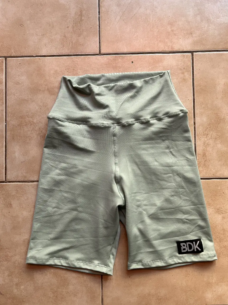 biker deportivo de mujer, color verde, con cintura alta y logo de la marca BDK. Ideal para entrenamientos y actividades físicas.