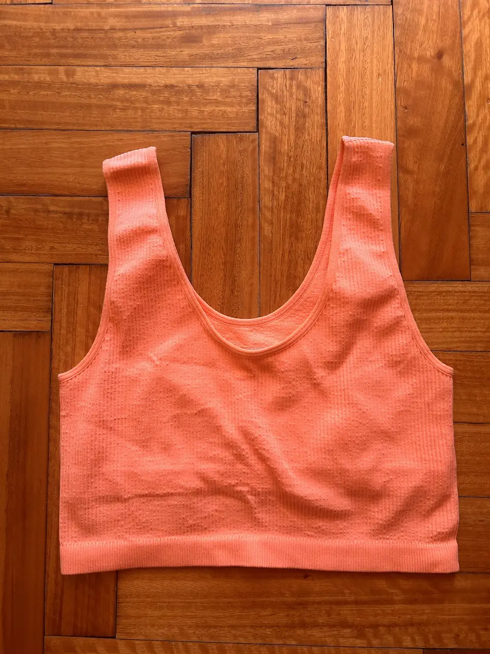 Top deportivo naranja sin costuras, ideal para entrenamientos. Diseño cómodo y transpirable.