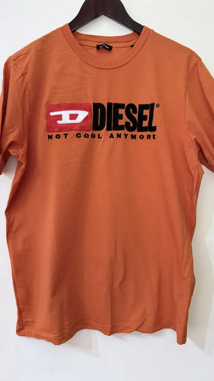 Remera Diesel naranja con estampado frontal. Cuello redondo y manga corta. Talle M.
