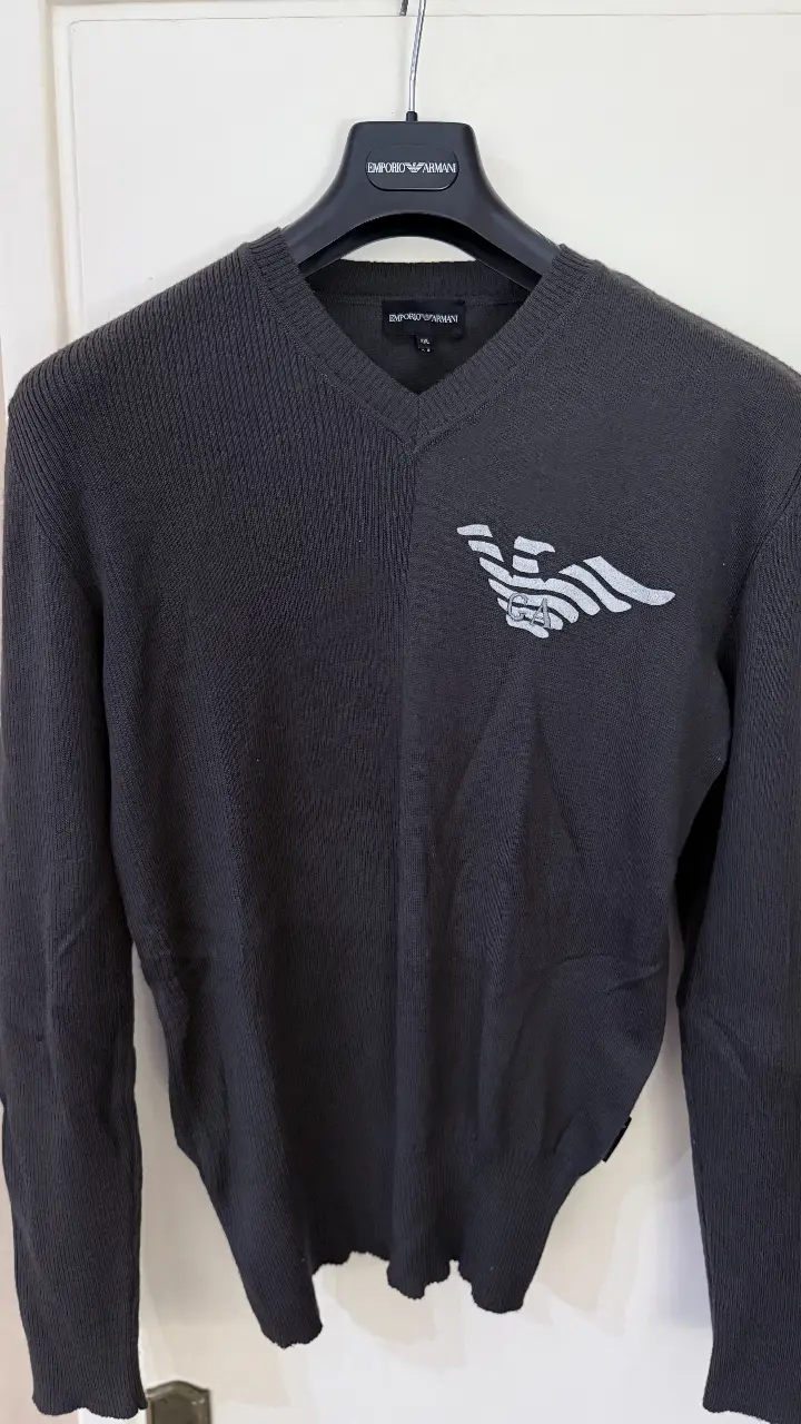 Sweater en V de Emporio Armani, color gris oscuro, con logo de la marca en blanco. Ideal para un look casual y elegante. 